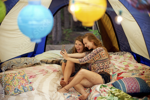 Girls taking selfie with cell phone in camping tent photo