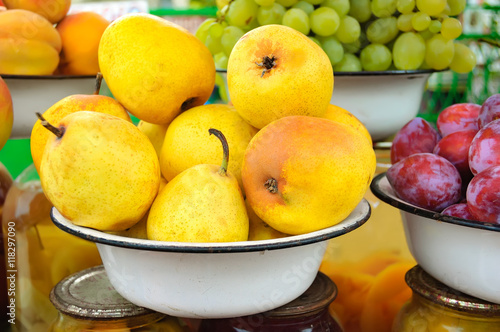 Farm market photo with ripe pear and other different fruits in white bowls - shallow depth of field.