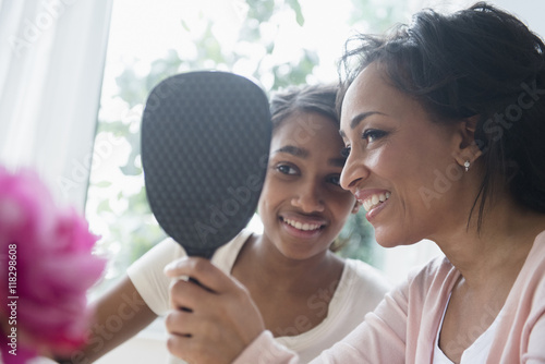 Mother and daughter looking in handheld mirror photo