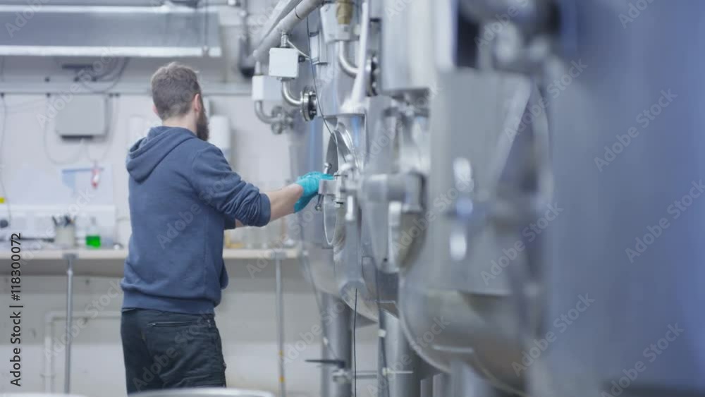 Worker in a brewery cleaning out the tanks with a water hose Worker in a brewery cleaning out the tanks with a water hose
