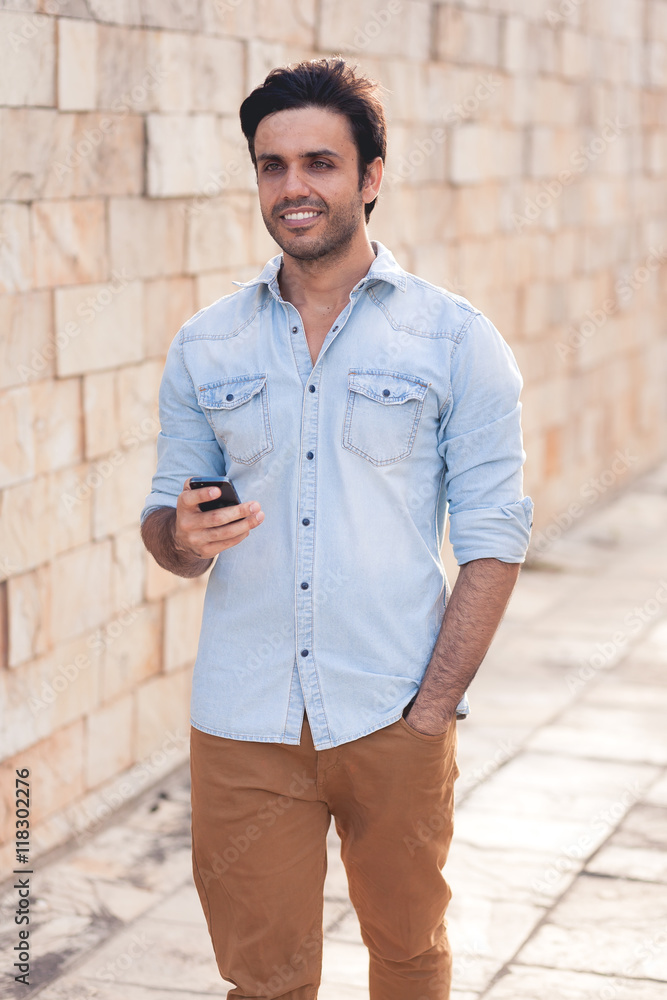 Outdoor portrait of modern young man with mobile phone in the street