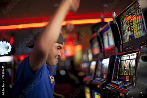 Cheering Native American man playing slot machines in casino photo