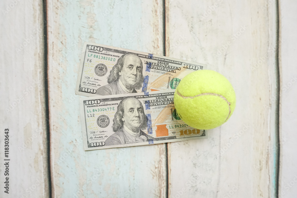Money and tennis balls on wooden floor