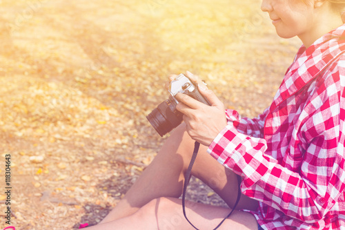 Tourist young woman holding vintage old photo camera in outdoor photo