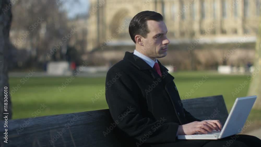 Portrait of businessman using laptop in city park area Portrait of businessman using laptop in city park area