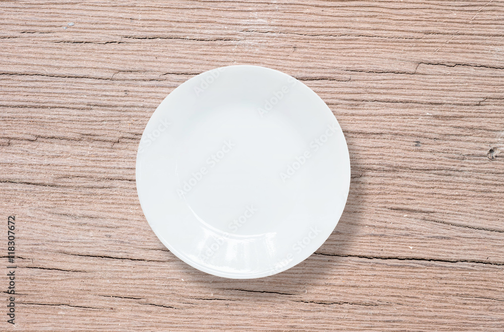 Closeup white ceramic dish on wood dining table textured background in top view Closeup white ceramic dish on wood dining table textured background in top view