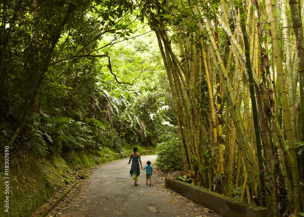 Mixed race mother and child walking on road in jungle Mixed race mother and child walking on road in jungle