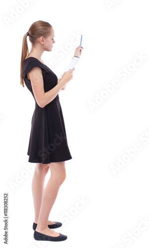 back view of  stands woman takes notes in a notebook. girl  watching. Rear view people collection.  backside view of person.  Isolated over white background. Blonde in a short black dress check the