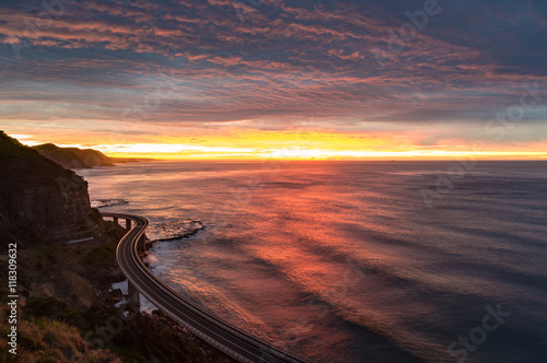 Sea Cliff Bridge on sunrise with beautiful dramatic sky and ocean shore on the background. The Bridge is part of highway Grand Pacific Drive scenic route. NSW, Australia