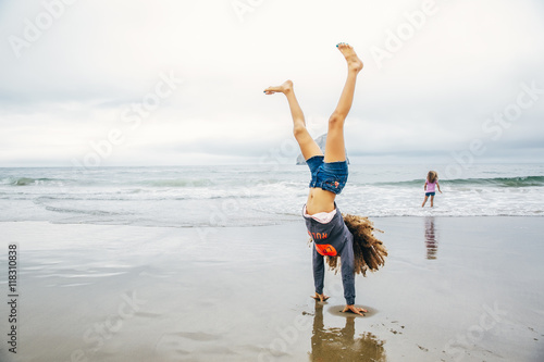Mixed race girl doing handstand on beach