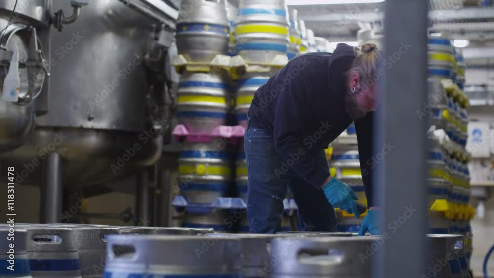 Worker in a brewery preparing barrels of beer for distribution Worker in a brewery preparing barrels of beer for distribution