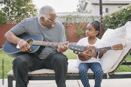 African American grandfather teaching granddaughter to play guitar