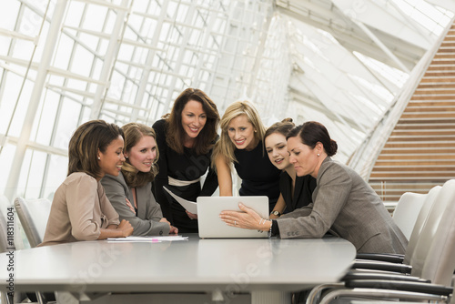 Busy businesswomen using laptop in meeting photo