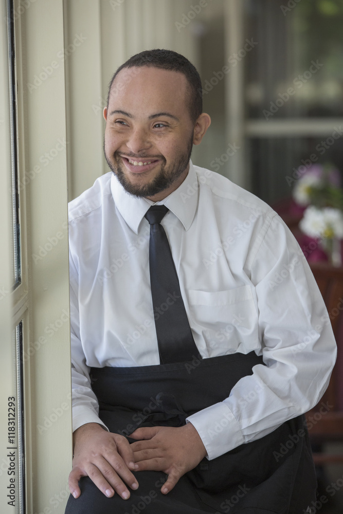 Mixed race server with down syndrome smiling in restaurant Mixed race server with down syndrome smiling in restaurant