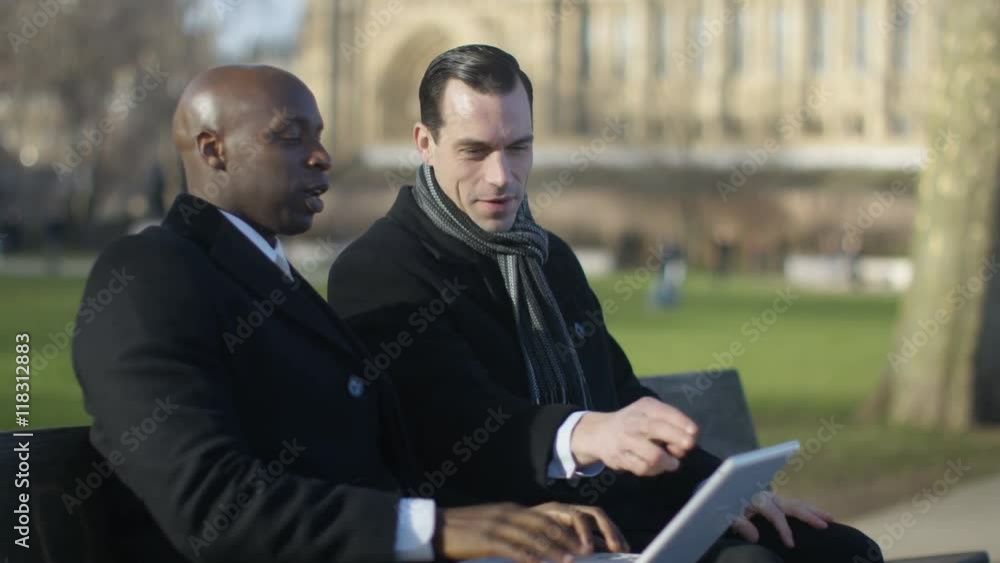 Businessmen using technology at outdoor meeting in the city Businessmen using technology at outdoor meeting in the city