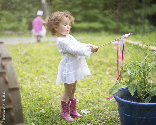 Girl playing with wand in backyard garden photo