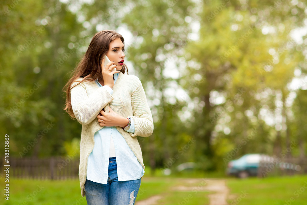 girl in a white jacket, blue shirt and blue jeans, call on the phone and looking away girl in a white jacket, blue shirt and blue jeans, call on the phone and looking away