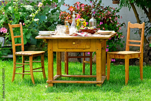Ländlich gedeckter Tisch mit Stühlen im Garten