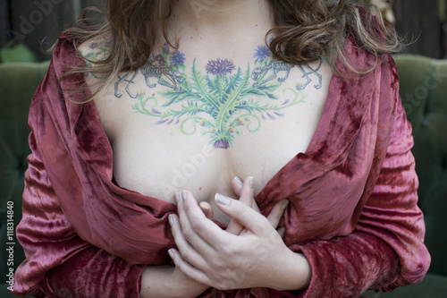 Caucasian woman in bathrobe displaying chest tattoos photo