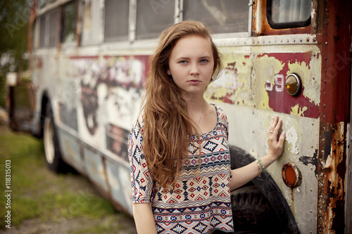 Caucasian teenage girl standing near dilapidated bus photo