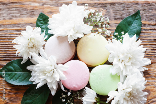 Sweet closeup photo of french traditional cookies. Lovely macaroon with flowers on the wooden background.