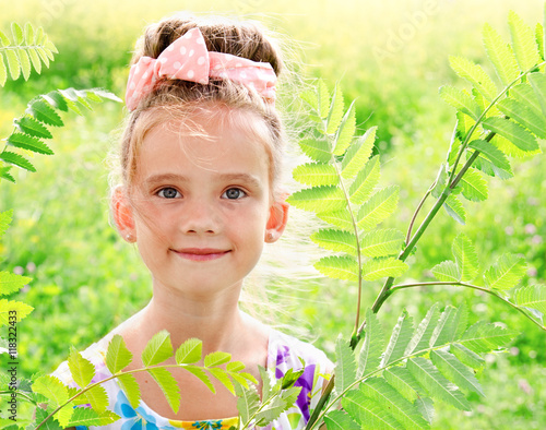 Adorable smiling little girl on the meadow in summer day