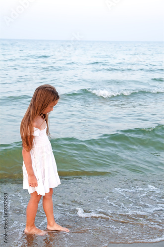 Adorable little girl is walking on the sea coast