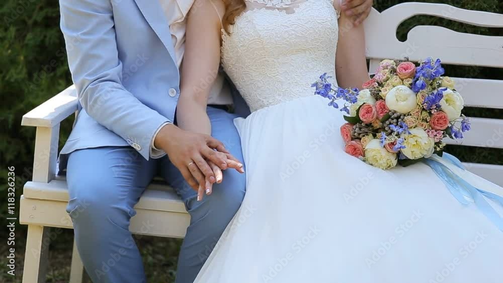The couple sitting on the white bench, holding hands The couple sitting on the white bench, holding hands