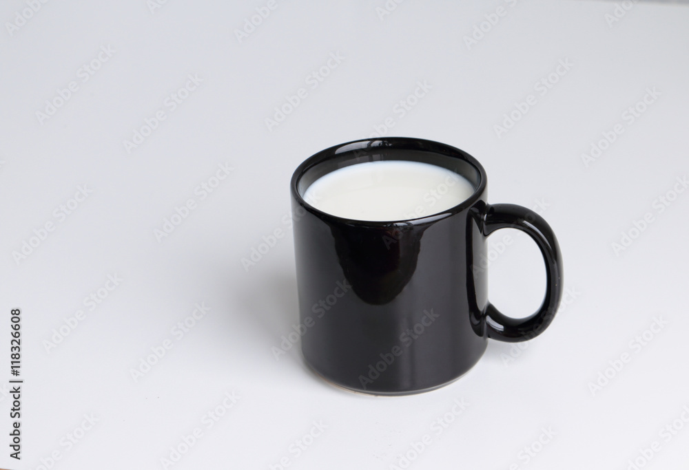 Black mug of milk on white background. Copy space. Black mug of milk on white background. Copy space.