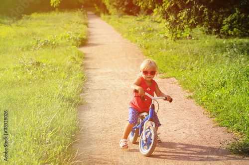 cute little girl riding runbike in summer photo