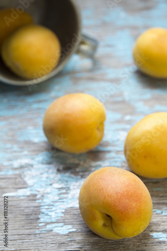 Apricots rolled out on rustic wooden surface from aluminum mug.