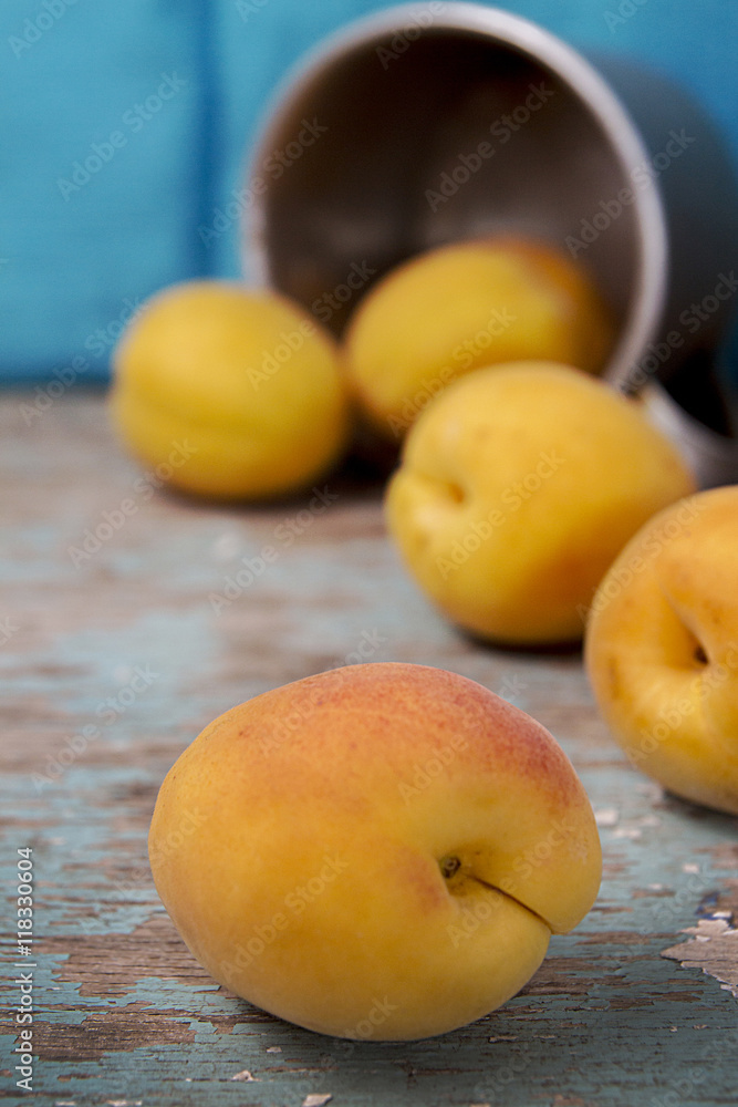 Apricots rolled out on rustic wooden surface from aluminum mug. Apricots rolled out on rustic wooden surface from aluminum mug.
