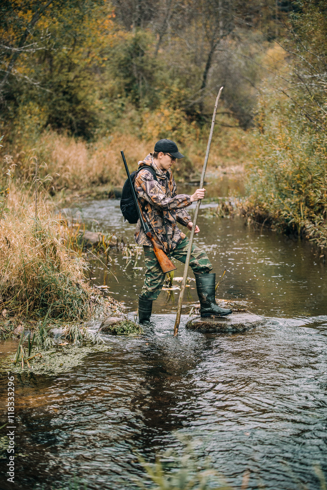 Male hunter enters the forest river.