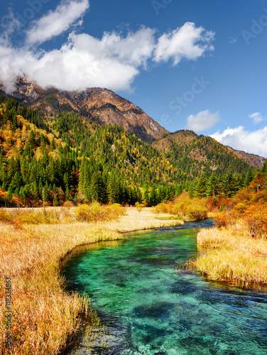 Beautiful river with azure crystal clear water among fall fields