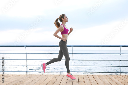 Young woman running on pier