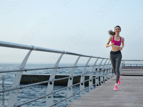 Young woman running on pier