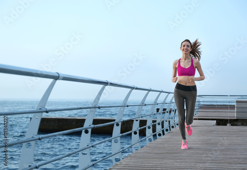 Young woman running on pier