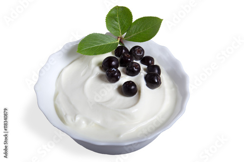 Йогурт с ягодой в чаше на белом фоне.\Белый йогурт с ягодой в чаше,зелёные листочки,фон изолированный.