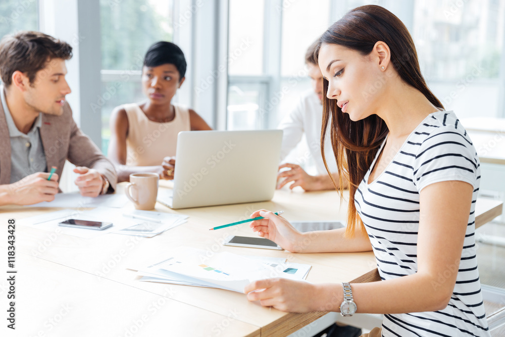 Concentrated young woman working with her business team in office Concentrated young woman working with her business team in office