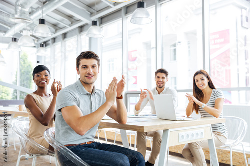 Smiling young business people applauding for presentation in office