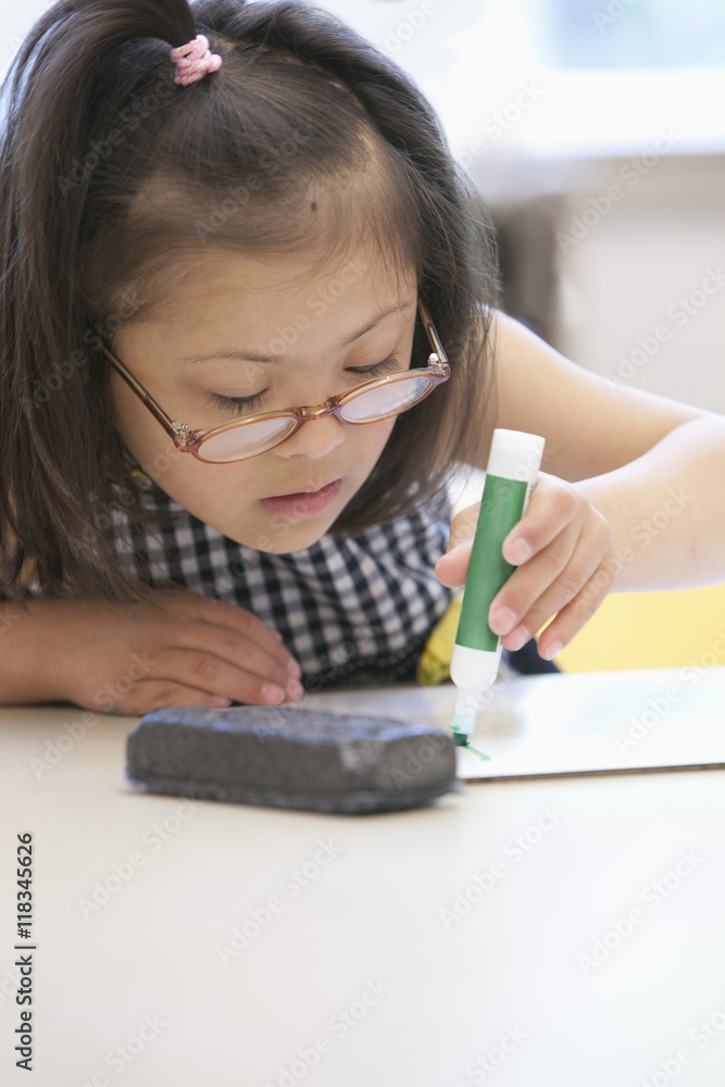 Mixed race Down syndrome student drawing in class foto de Stock Adobe