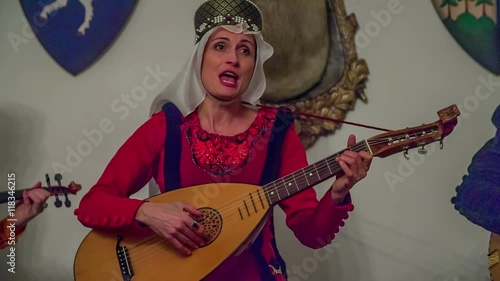 A princess is singing and playing a tambura from her heart. Other members of the royal family are helping her and performing with her. Close-up shot. She is having a beautiful ring on her finger.
 photo