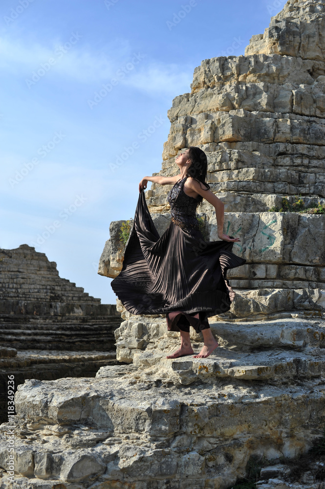 young attractive fashion women posing on the rocks with fashion dress
