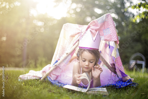 Girl reading in tent in backyard photo