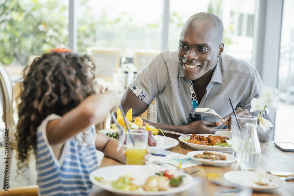 Smiling father and daughter eating food at restaurant Smiling father and daughter eating food at restaurant