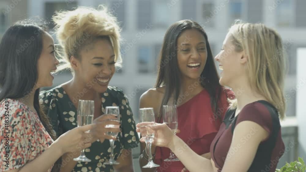 Beautiful female friends drinking & socializing on city rooftop Beautiful female friends drinking & socializing on city rooftop