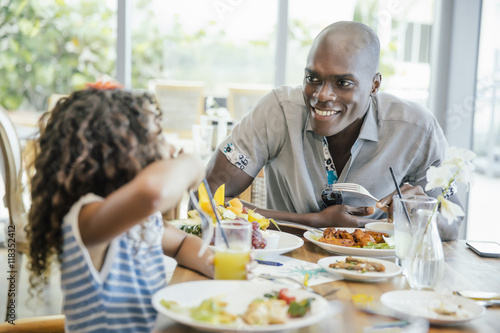 Wallpaper Mural Smiling father and daughter eating food at restaurant Torontodigital.ca
