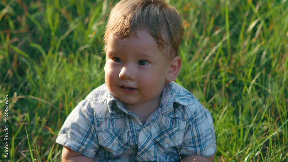 close up portrait of happy baby on green grass background in slow motion close up portrait of happy baby on green grass background in slow motion
