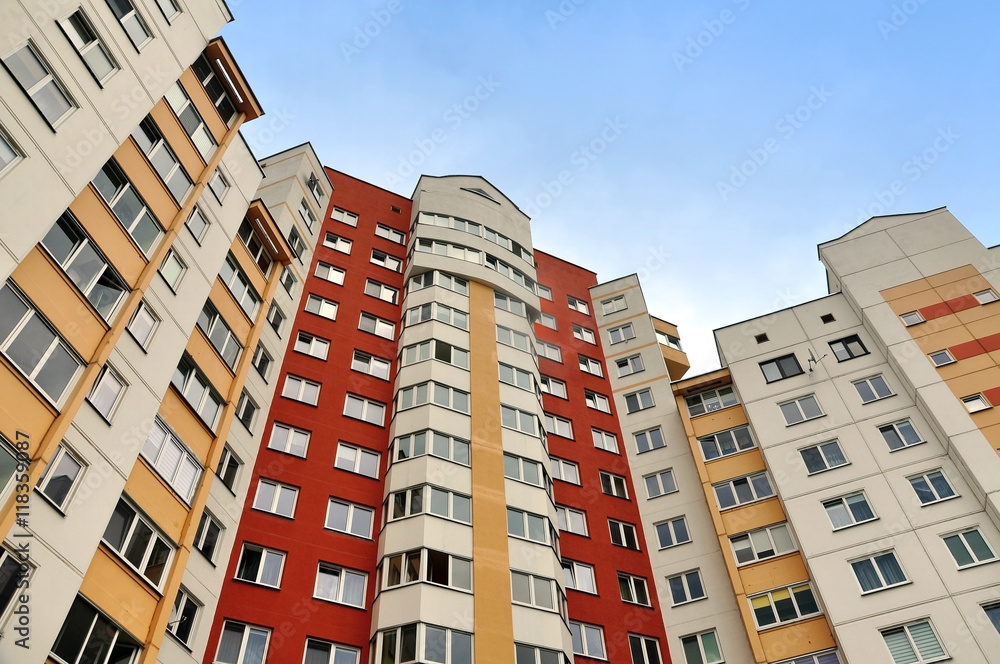Facade of a modern multistory residential building of red, yellow and white color. Look up. 