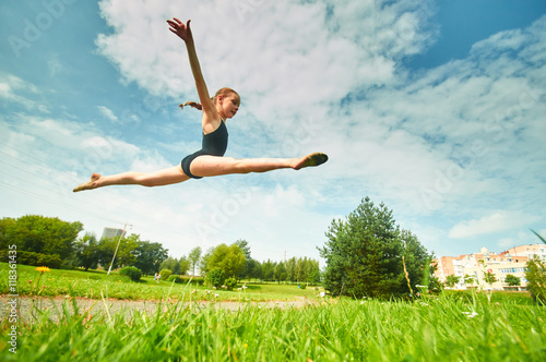 Young beautiful preteen girl doing gymnastics outdoors
